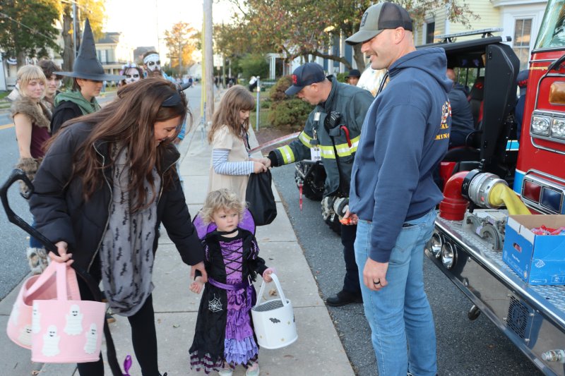 Heather Mulvihill, and her daughter Leela, left, stop to get candy from Robbie Stephens, Lewes fire chief.